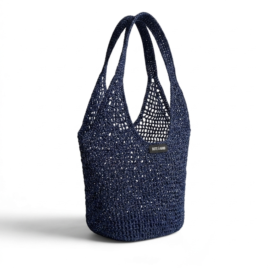 Side view of dark blue raffia bag showing flexible structure and metallic woven finish by Bote A Mano.