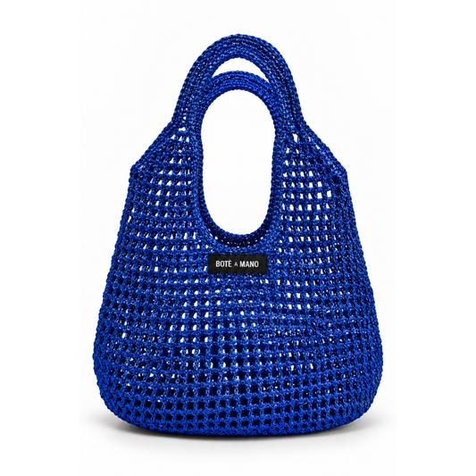 Blue woven handbag with 'Boté a Mano' label on a white background