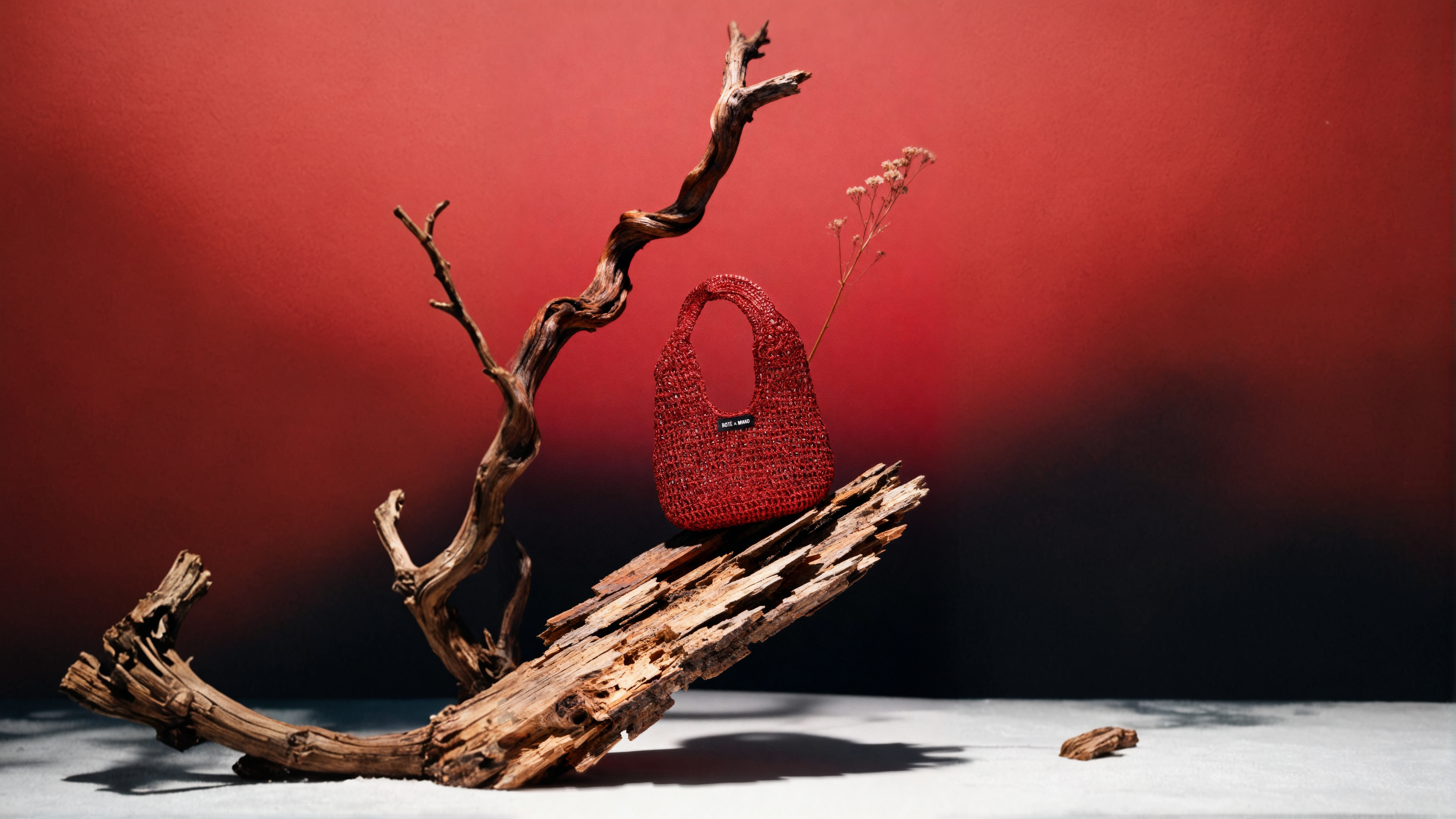 Red handbag on a piece of driftwood with a red background
