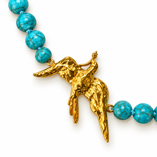 Close-up of turquoise beads and sculptural 24K gold-plated bird pendant by Bote A Mano