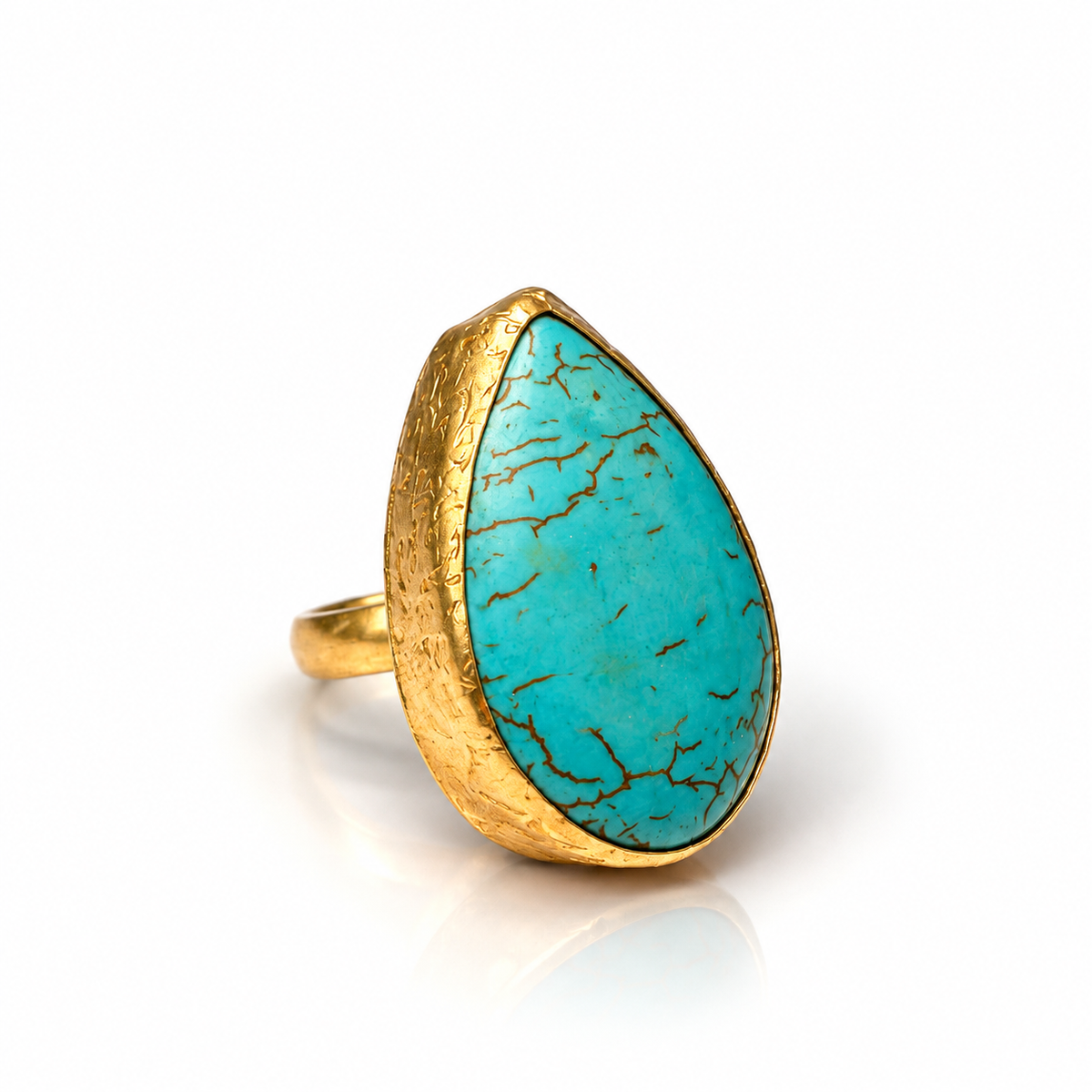 A gold ring featuring a large, teardrop-shaped turquoise stone with natural brown matrix veining, set against a clean white background.