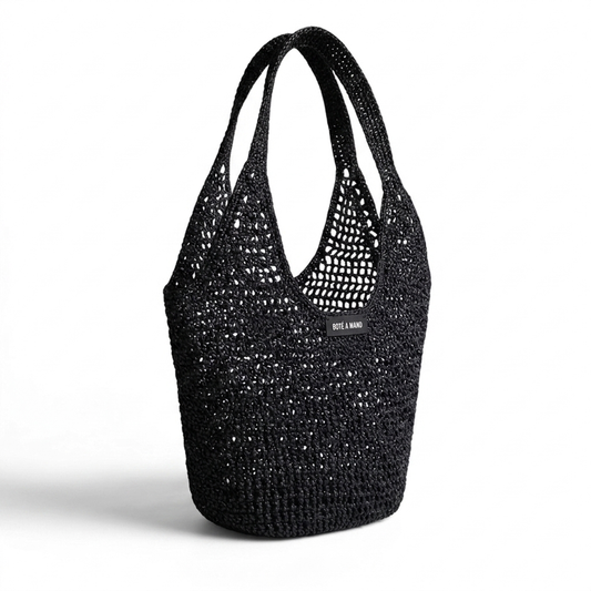 Side view of black raffia bag showing flexible structure and artisanal woven craftsmanship by Bote A Mano