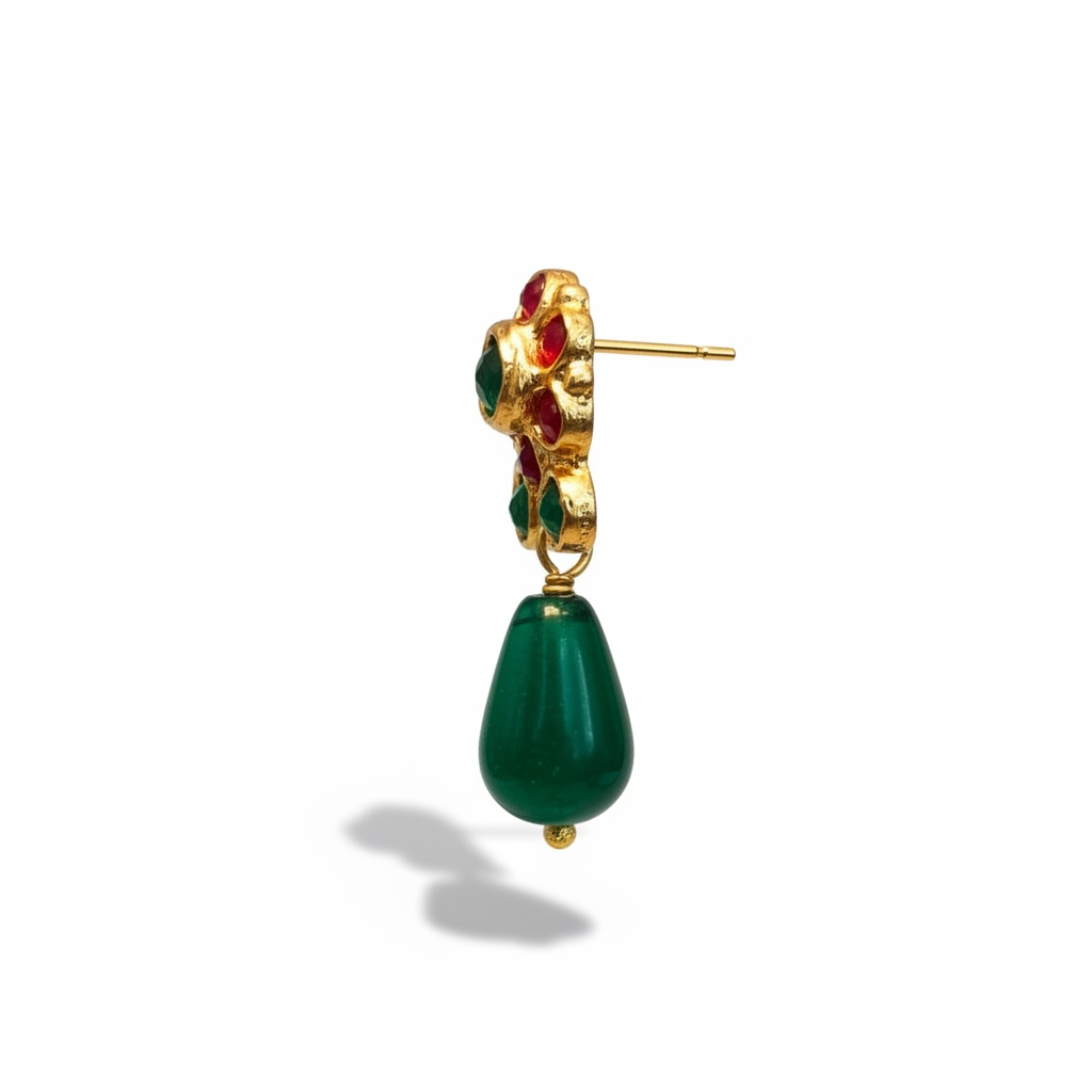 Close-up of gold-plated emerald and ruby earrings showing vibrant gemstone contrast and intricate texture.