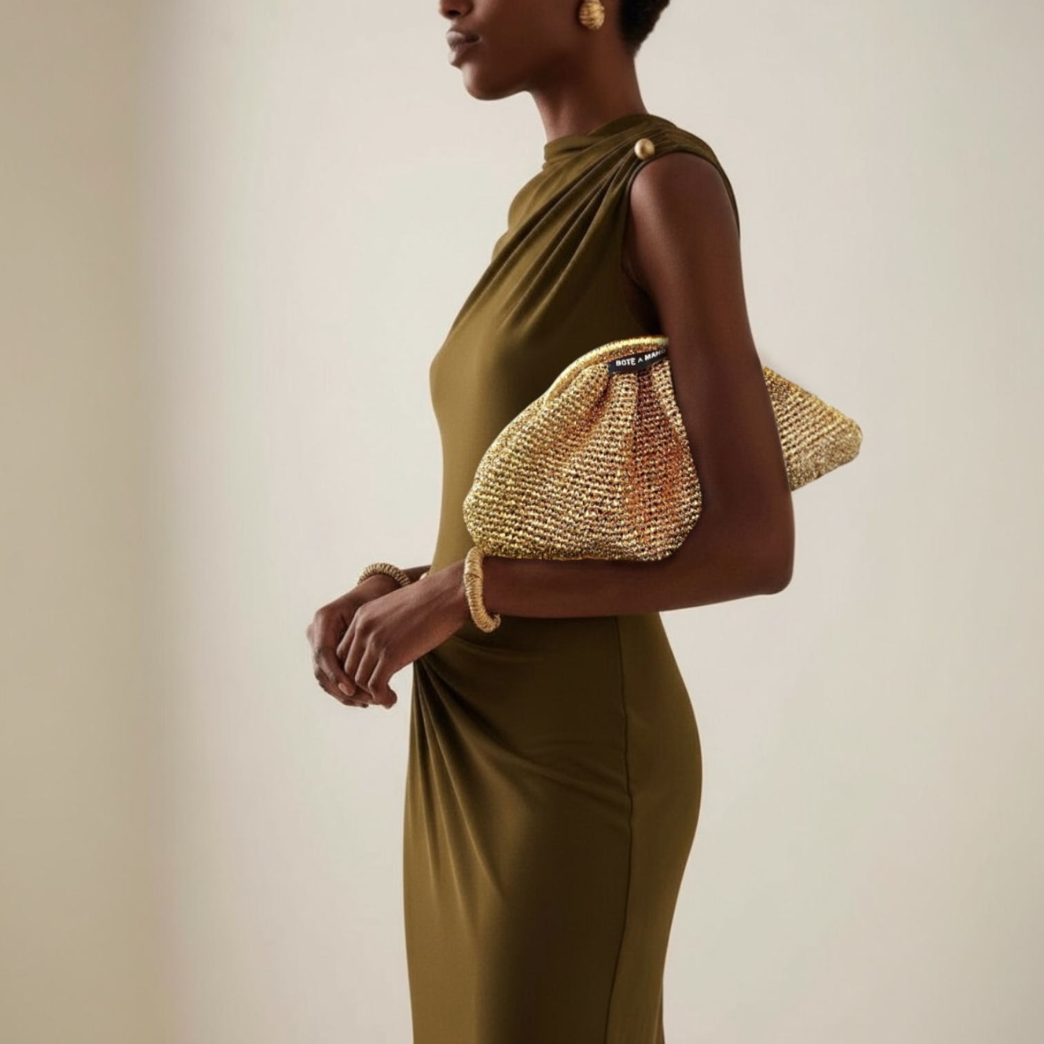 Elegant model holding the metallic gold evening bag against a white dress, highlighting it as a perfect wedding clutch accessory.