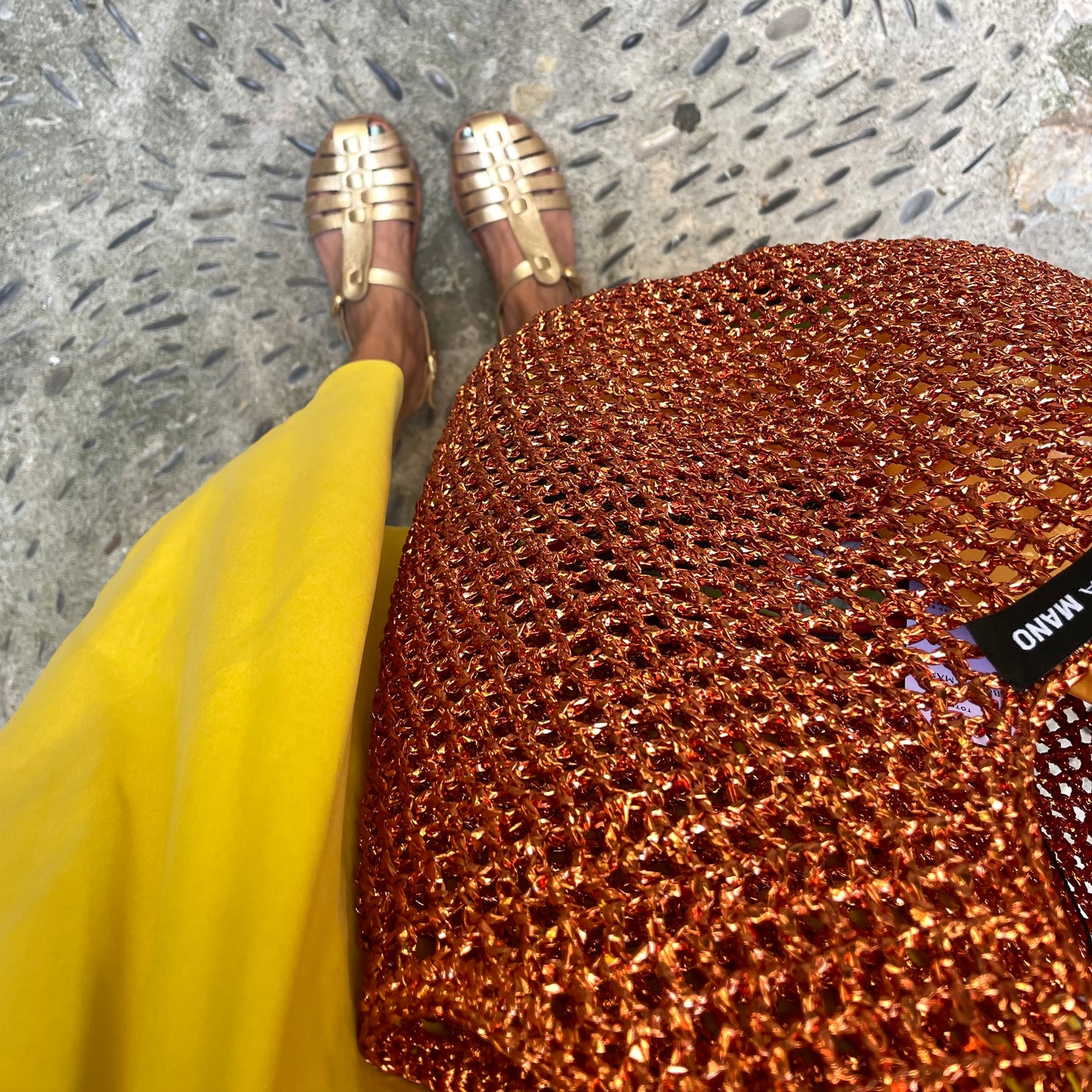 Model carrying orange copper metallic raffia bag by Bote A Mano in an elegant lifestyle setting